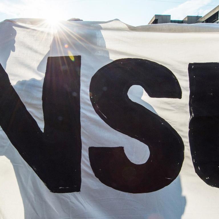 Ein Demonstrant hält bei einer Kundgebung ein Banner mit der Aufschrift "NSU". München, 2018.