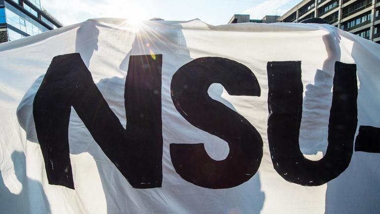 Ein Demonstrant hält bei einer Kundgebung ein Banner mit der Aufschrift "NSU". München, 2018.