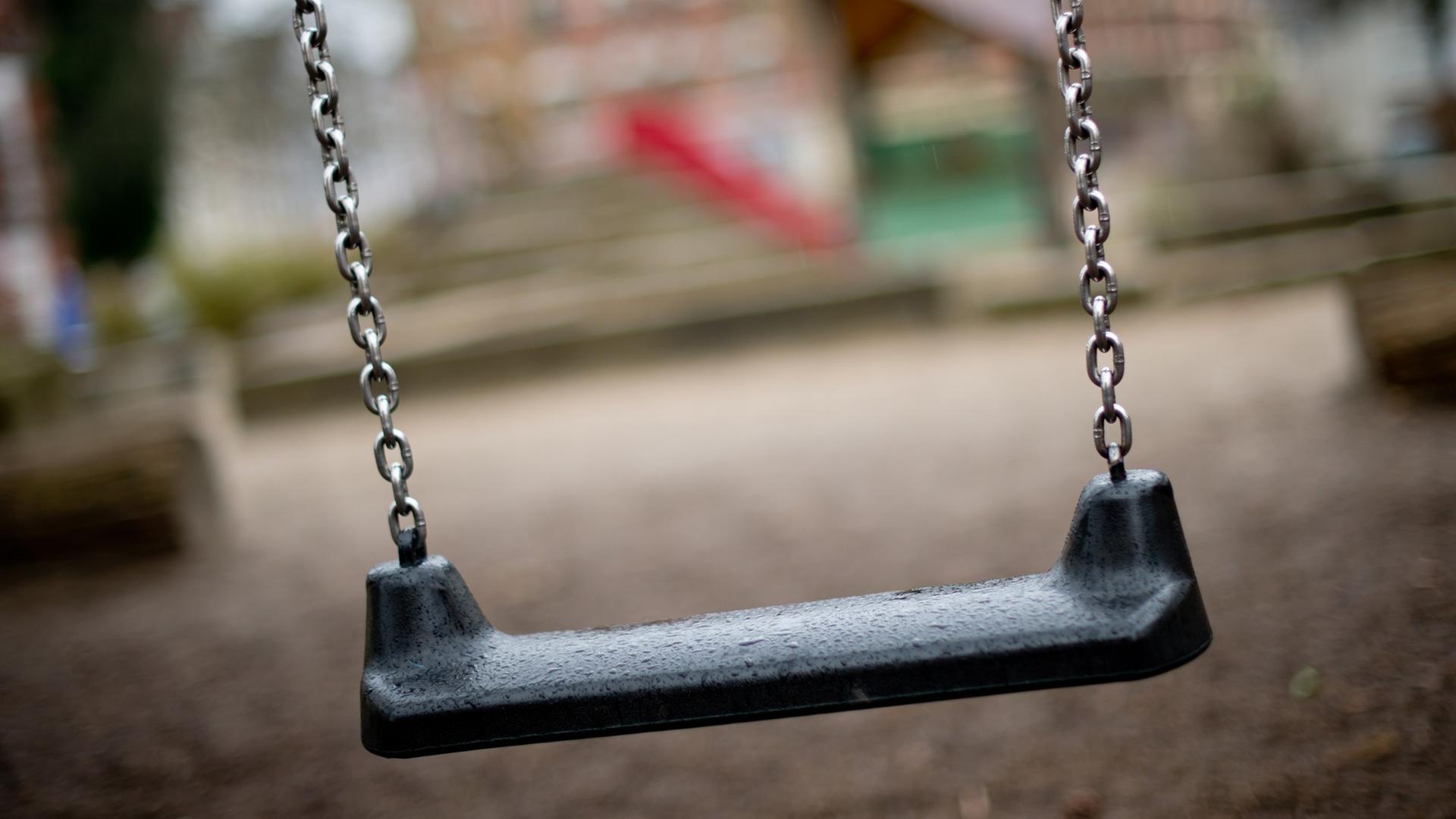 Eine leere Schaukel auf einem Spielplatz zu sehen Eine leere Schaukel auf einem Spielplatz zu sehen