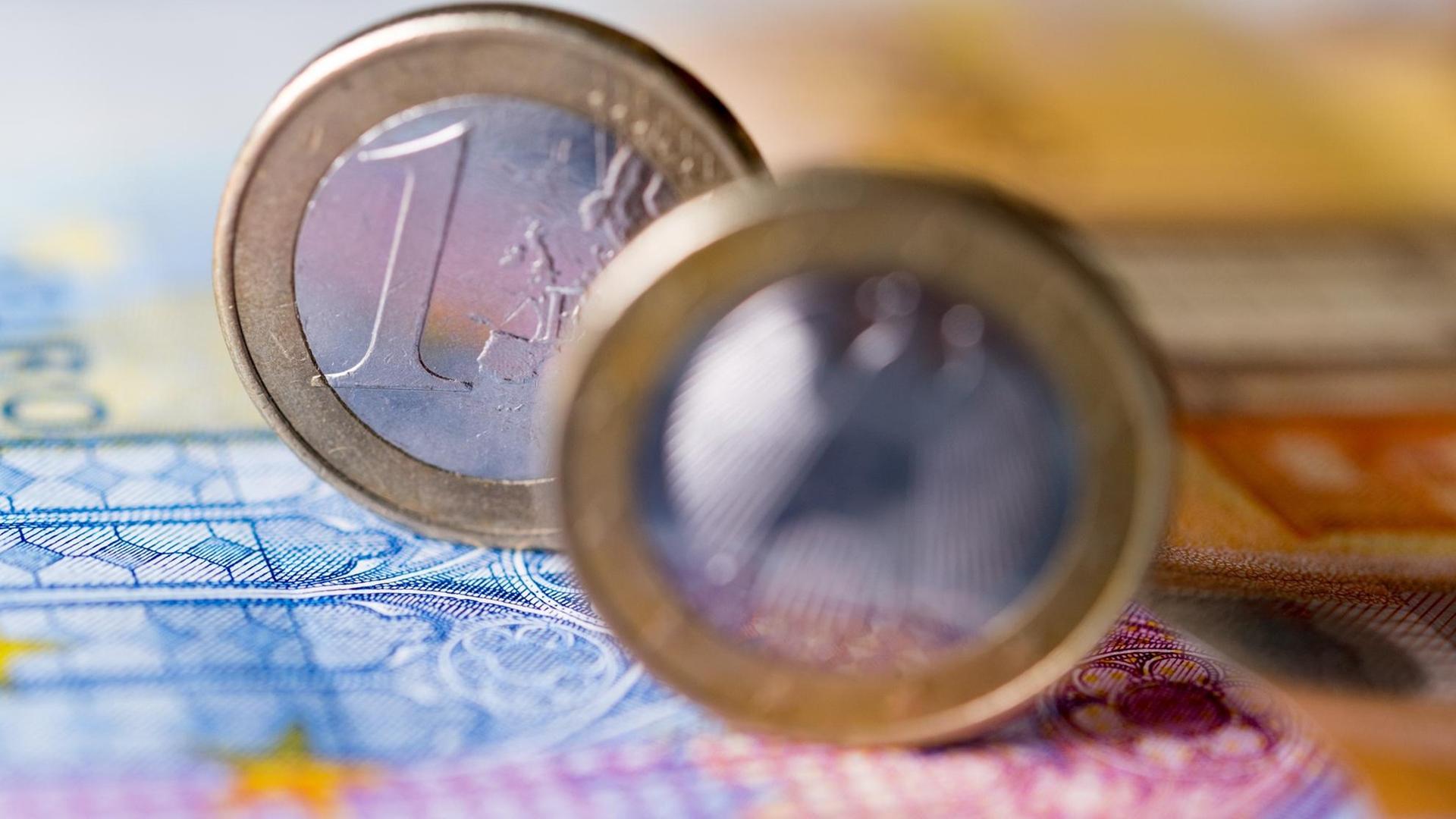 Zwei Ein-Euro-Münzen stehen auf einem Geldschein. Zwei Ein-Euro-Münzen stehen auf einem Geldschein.