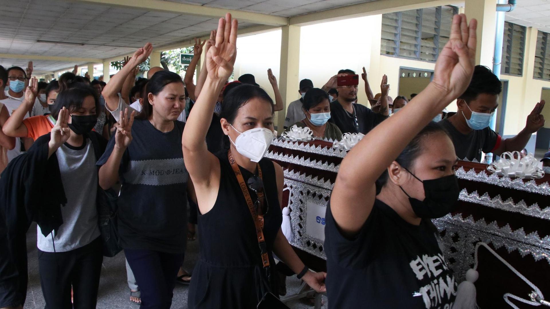 Menschen in Myanmar tragen den Sarg von einer Frau, die Soldaten getötet haben. Menschen in Myanmar tragen den Sarg von einer Frau, die Soldaten getötet haben.