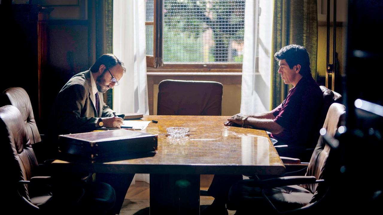 Im Still aus "Il Traditore" sitzt Pierfrancesco Favino an einem schweren Holztisch Fausto Russi Alesi gegenüber. Im Still aus "Il Traditore" sitzt Pierfrancesco Favino an einem schweren Holztisch Fausto Russi Alesi gegenüber.