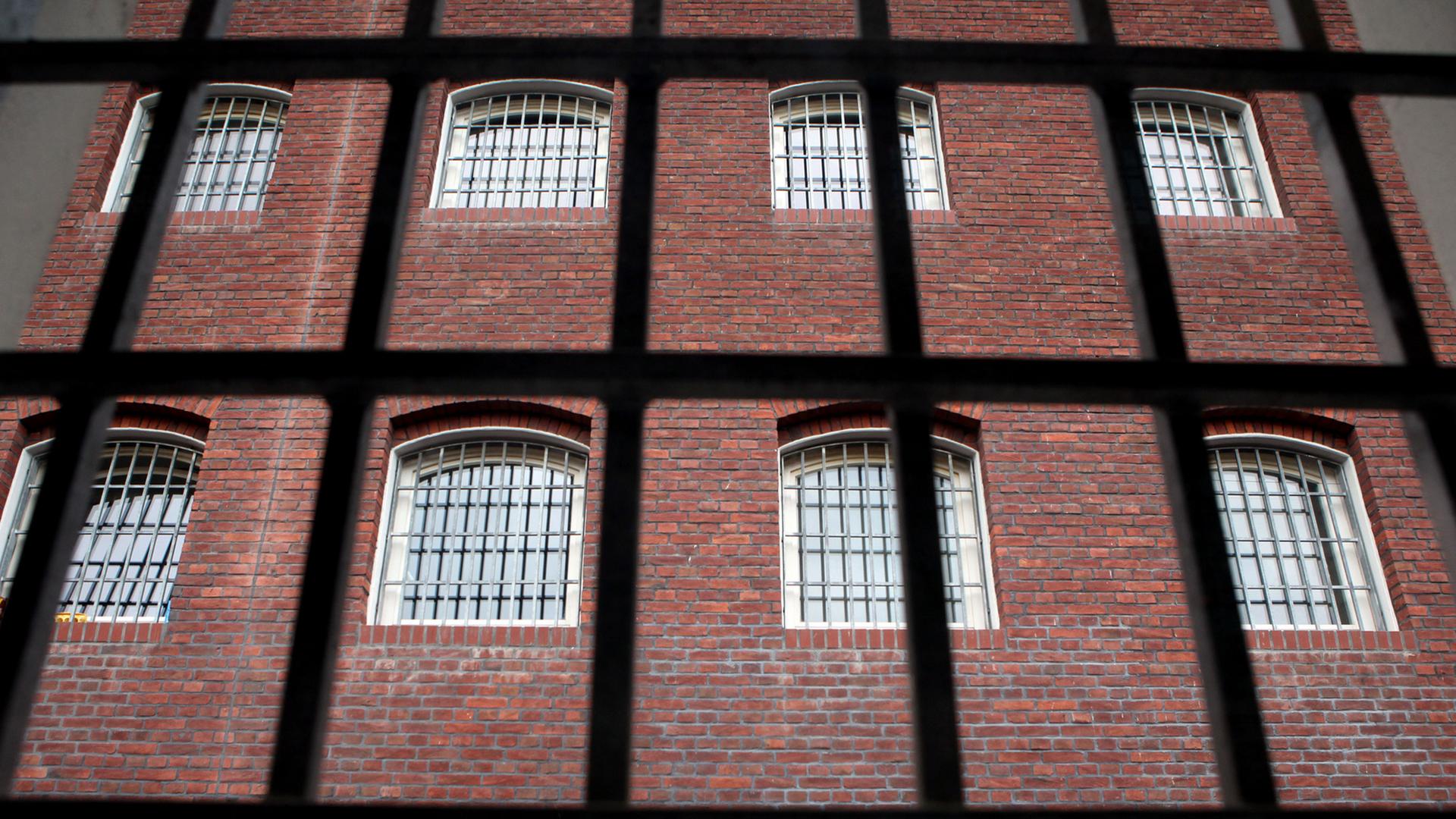 Blick durch ein vergittertes Fenster auf ein altes Hafthaus in der JVA Waldheim