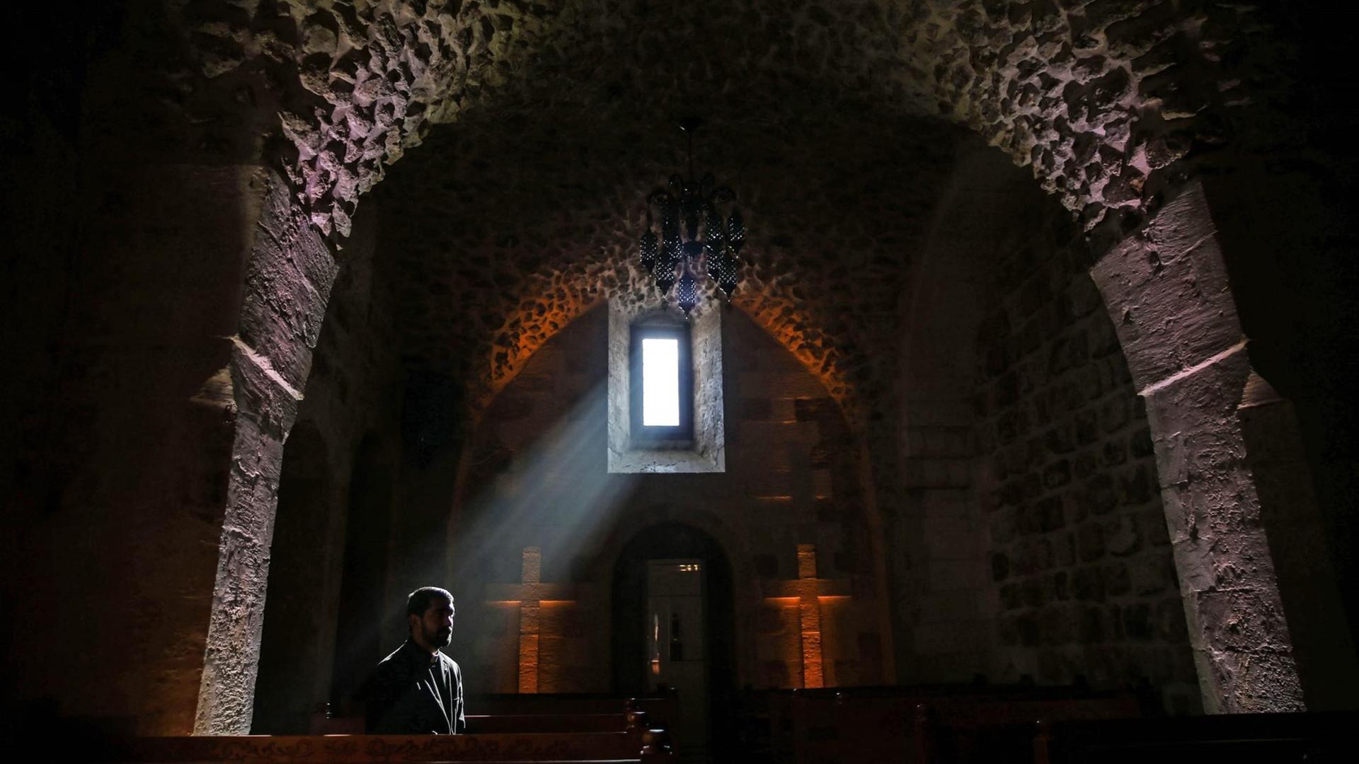 Die Silhouette eines Mannes in der assyrisch-protestantischen Kirche, auf den ein Lichtstahlt durch das Fenster fällt