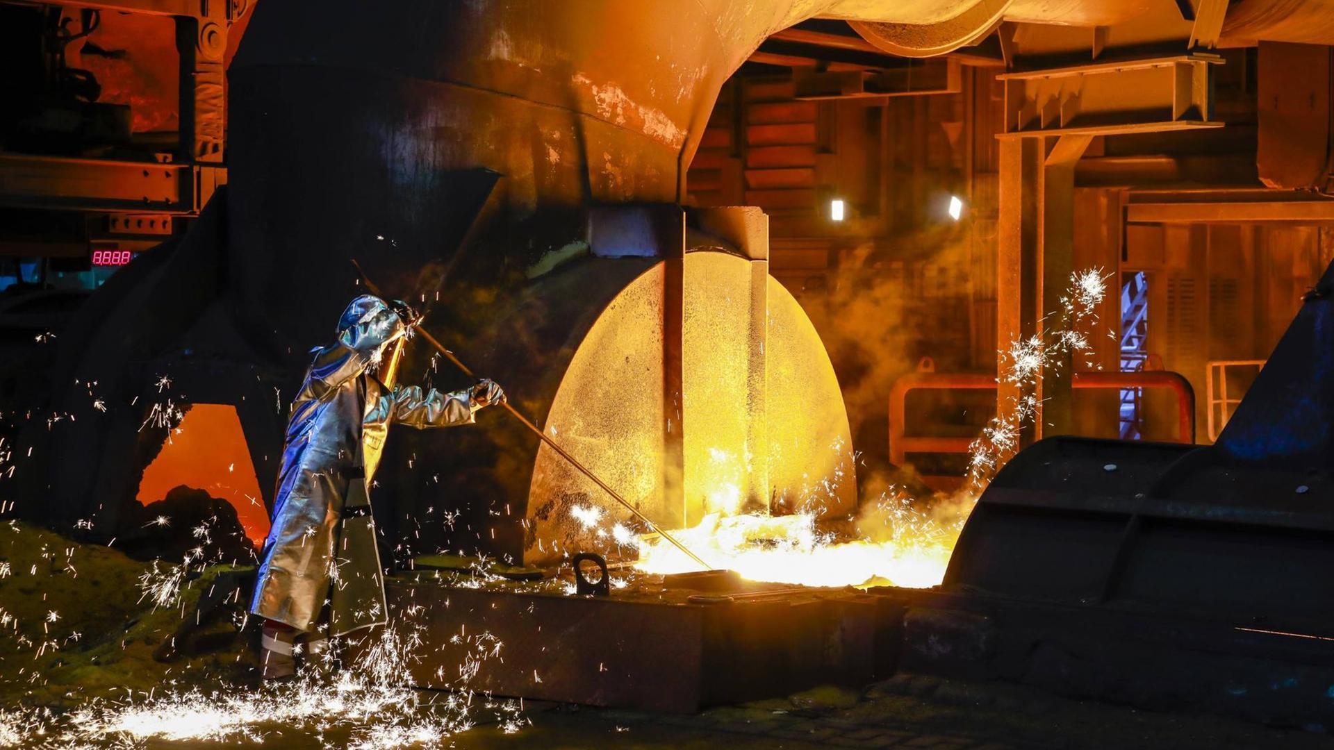 Stahlarbeiter im Schutzanzug entnimmt eine 1.500 Grad heiße Roheisenprobe beim Abstich am Hochofen im Stahlwerk Thyssen Krupp Steel in Duisburg, 15.04. 2019