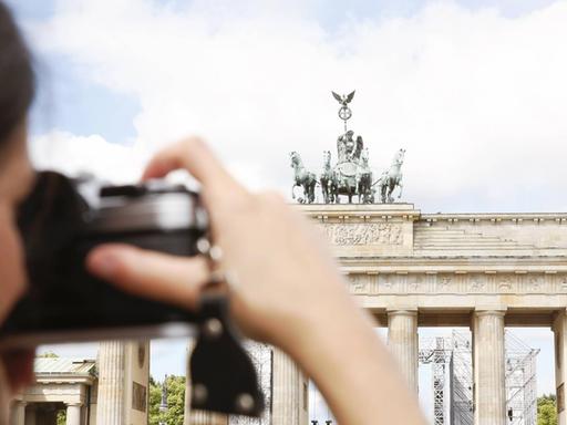 Eine Frau fotografiert das Brandenburger Tor in Berlin