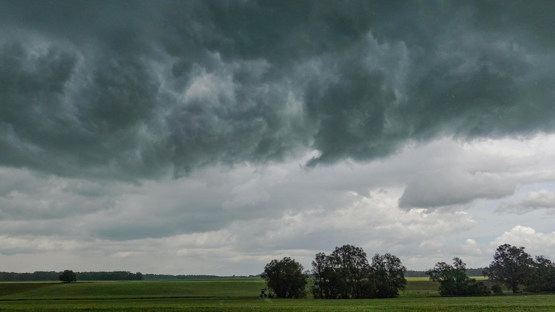 Dunkle Gewitterwolken über einer grünen Landschaft Dunkle Gewitterwolken über einer grünen Landschaft