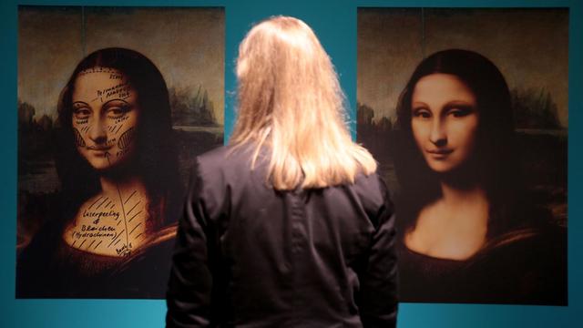 Eine Frau steh vor zwei Bildern der Mona Lisa mit Vorschlägen für eine Schönheitsoperation.