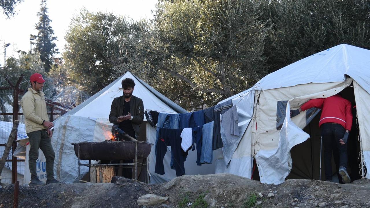 An einem offenen Feuer wärmen sich im Flüchtlingscamp Moria einige Männer die Hände. An einem offenen Feuer wärmen sich im Flüchtlingscamp Moria einige Männer die Hände.