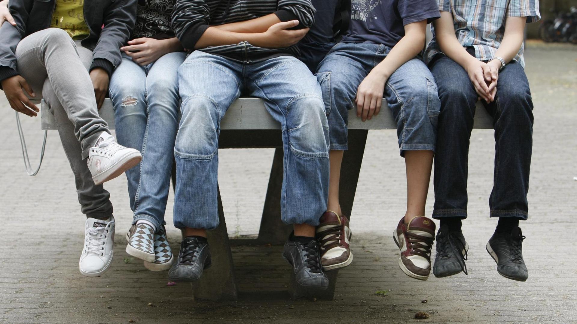 Schüler an einem Gymnasium sitzen nebeneinander auf einer Tischtennis-Platte. Schüler an einem Gymnasium sitzen nebeneinander auf einer Tischtennis-Platte.
