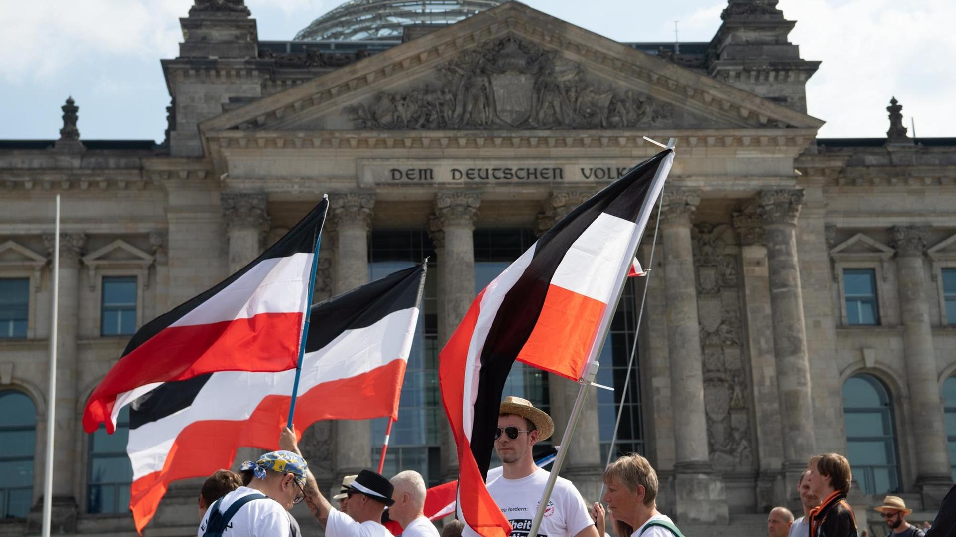 Mit ehemaligen Reichsfahnen stehen Demonstranten vor dem Reichstag. Mit ehemaligen Reichsfahnen stehen Demonstranten vor dem Reichstag.