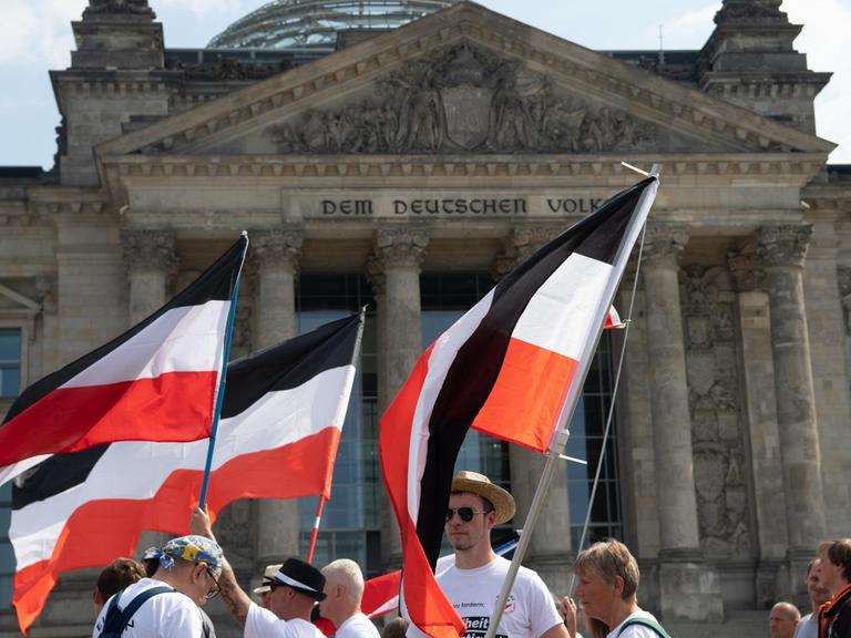Mit ehemaligen Reichsfahnen stehen Demonstranten vor dem Reichstag.