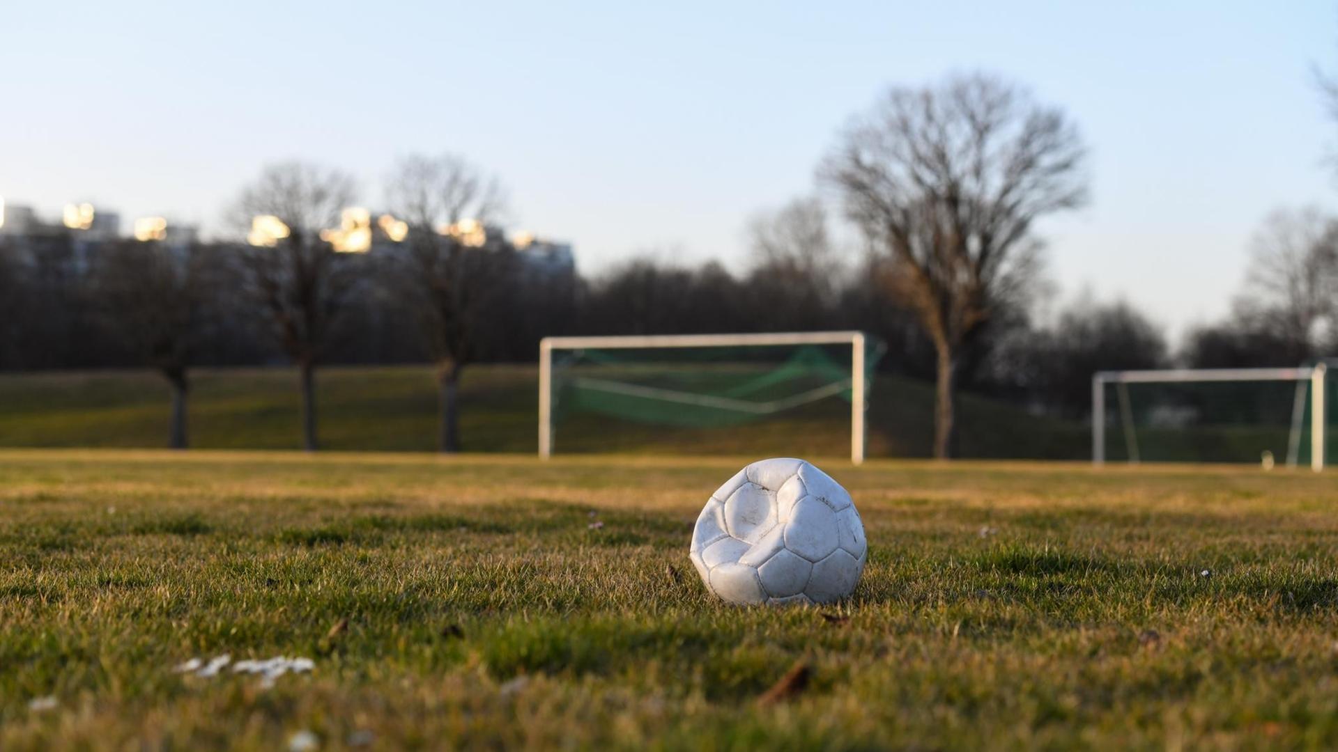 Ein eingedrückter Fußball liegt auf einem Fußballplatz. Ein eingedrückter Fußball liegt auf einem Fußballplatz.