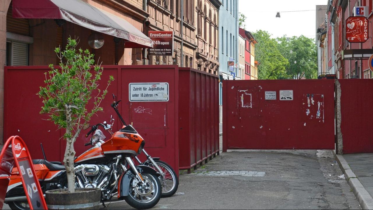 Blick auf das rote Eingangstor zur Lupinenstraße in Mannheim, mit zwei Motorrädern im linken Bildrand
