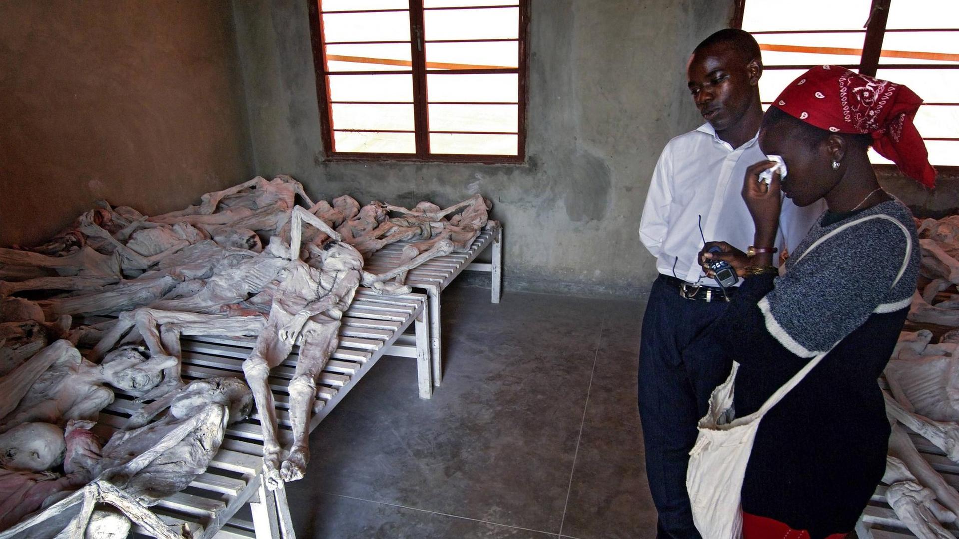 Eine Frau weint neben einem Mann in der Gedenkstätte Murambi in Ruanda am 24.05.2005 neben durch gelöschten Kalk mumifizierten Opfern des Genozids. Der Völkermord an den Tutsi in Ruanda schockierte 1994 die ganze Welt.