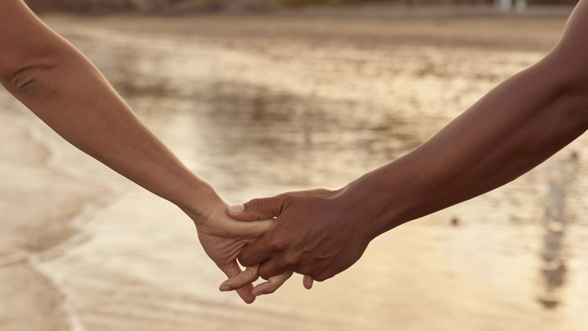 Ein Paar hält Händchen. Ein Männer- und ein Frauenarm halten sich an den Händen fest Ein Paar hält Händchen. Ein Männer- und ein Frauenarm halten sich an den Händen fest