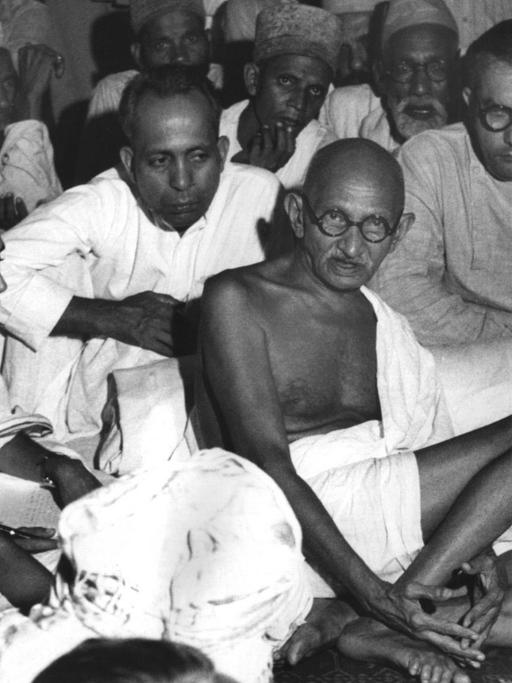 Gandhi sitzt in einer undatierten Aufnahme bei Muslimen in Neu-Delhi und versucht, die blutigen Auseinandersetzungen zwischen den Muslimen und den Hindus zu schlichten.
