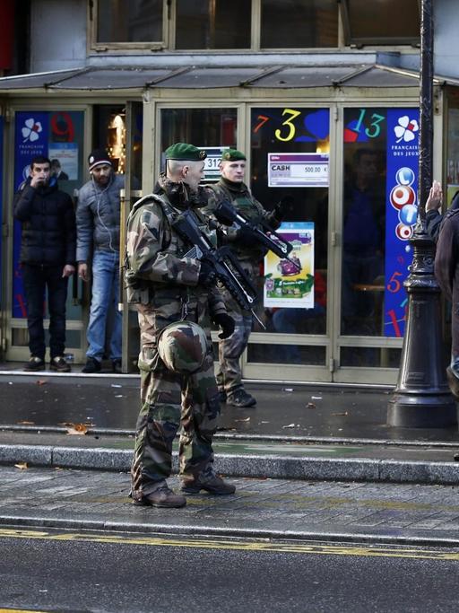 Straßenszene: mehrere Soldaten und Passanten stehen in der Nähe des Tatorts.