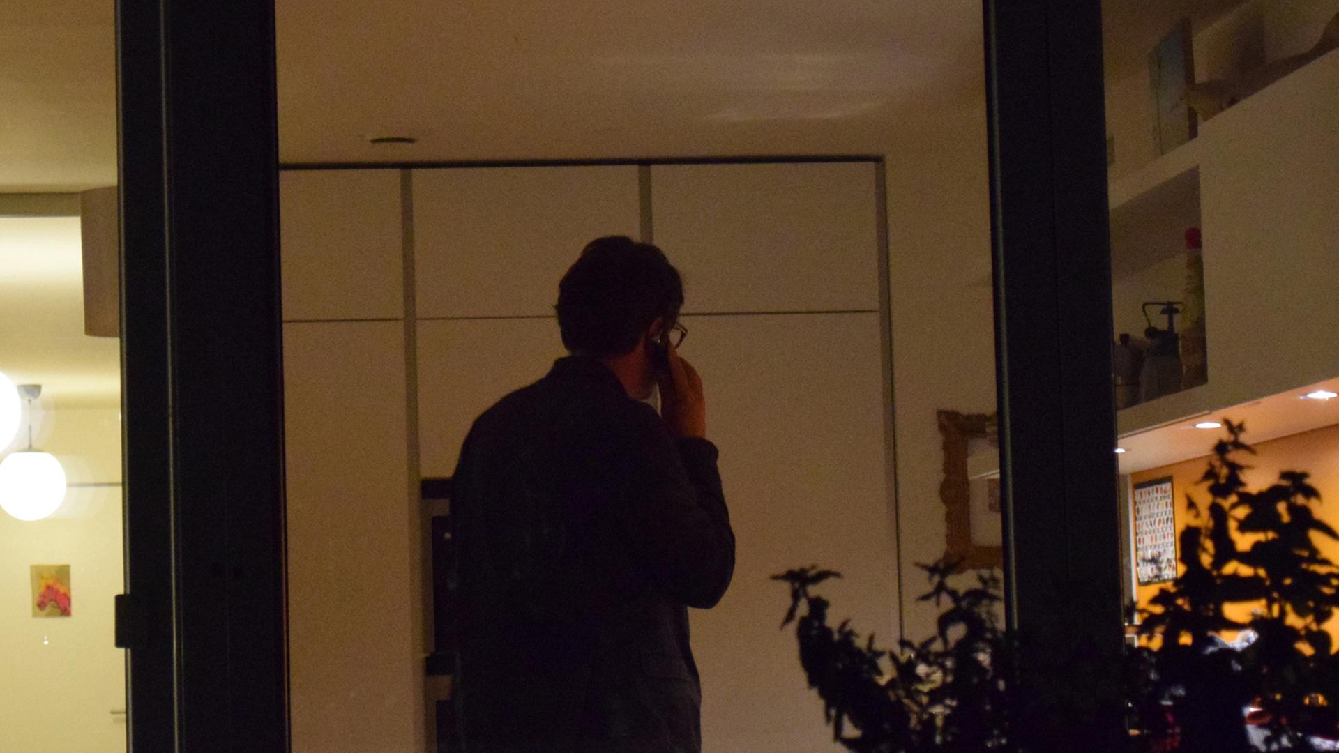Ein Mann telefoniert in einem Wohnzimmer. Ein Mann telefoniert in einem Wohnzimmer.