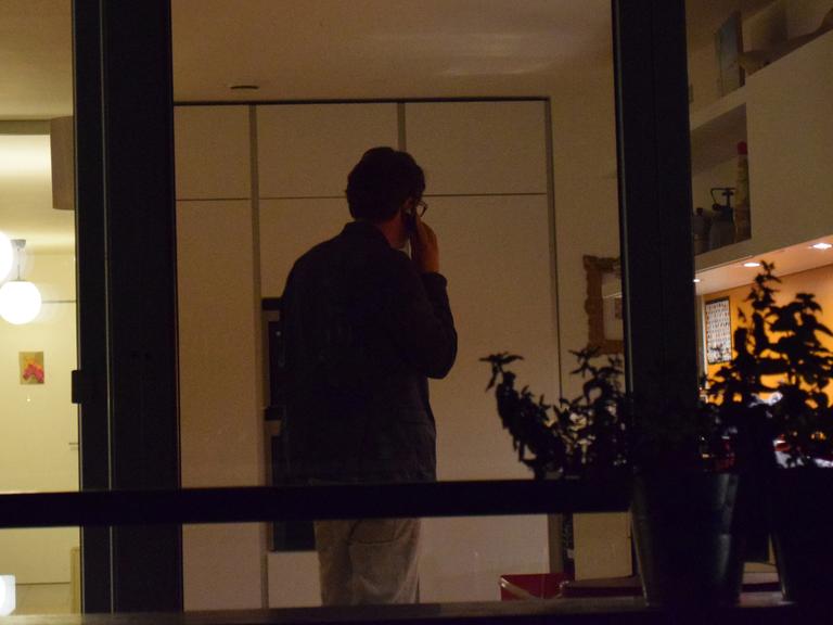 Ein Mann telefoniert in einem Wohnzimmer.