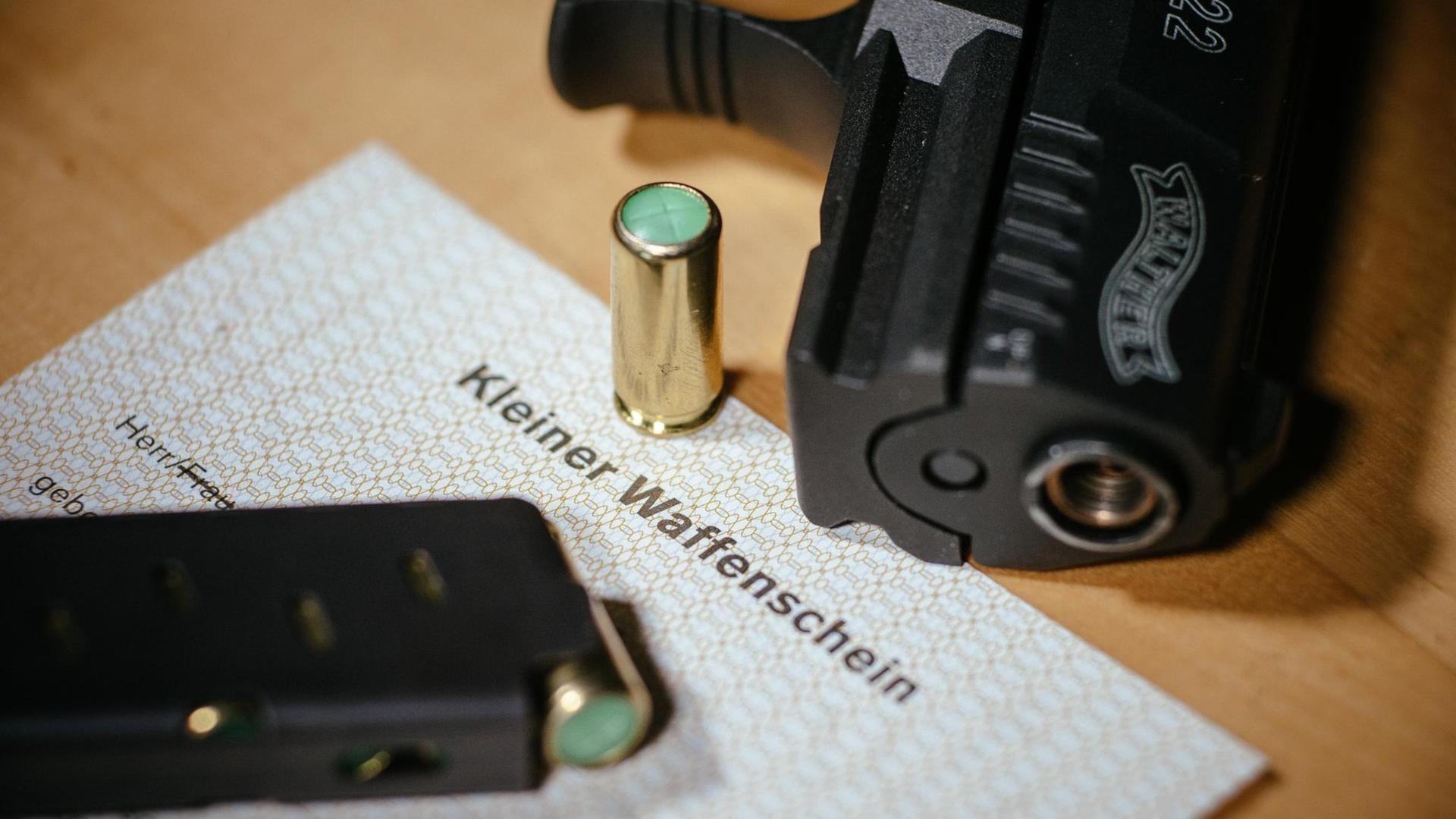 Ein Kleiner Waffenschein liegt zwischen einer Schreckschuss-Pistole "Walther P22", einem Magazin und einer Knallpatrone. Das Dokument berechtigt den Besitzer zum Tragen einer solchen Waffe in der Öffentlichkeit. Ein Kleiner Waffenschein liegt zwischen einer Schreckschuss-Pistole "Walther P22", einem Magazin und einer Knallpatrone. Das Dokument berechtigt den Besitzer zum Tragen einer solchen Waffe in der Öffentlichkeit.