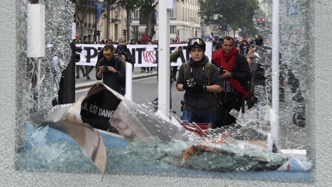 Das Bild ist durch die zerstörte Vitrine mit dem gebrochenen Sicherheitsglas hindurch fotografiert. Auf der anderen Seite sieht man vier Personen, die ebenfalls die Vitrine fotografieren. Das Bild ist durch die zerstörte Vitrine mit dem gebrochenen Sicherheitsglas hindurch fotografiert. Auf der anderen Seite sieht man vier Personen, die ebenfalls die Vitrine fotografieren.