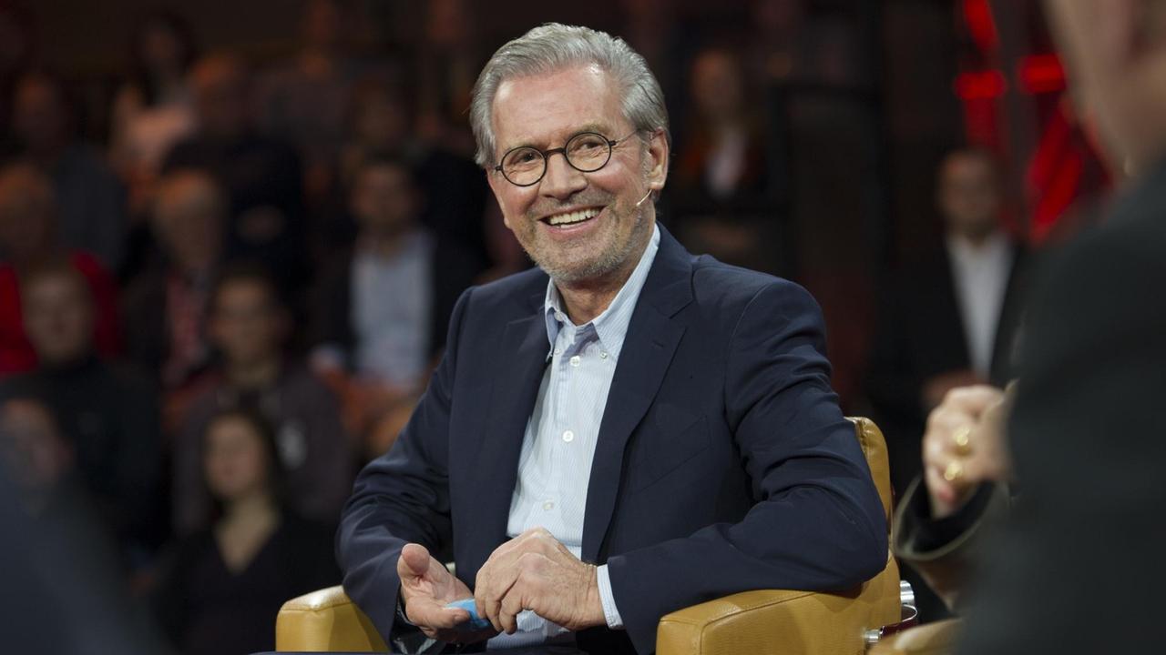 Jürgen Todenhöfer sitzt in einem Fernsehstudio und lacht in die Kamera. 