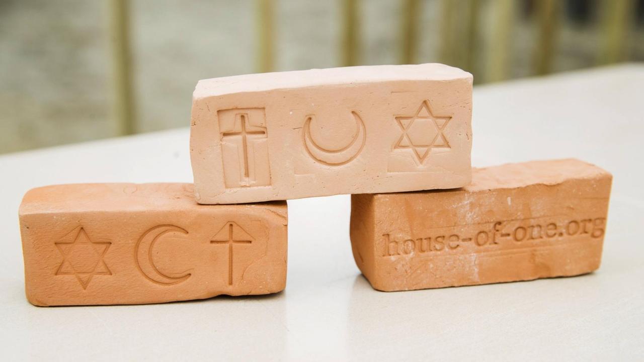 Drei Backsteine mit den eingestempelten Symbolen der Religionen: ein Stern, ein Halbmond und ein Kreuz. Drei Backsteine mit den eingestempelten Symbolen der Religionen: ein Stern, ein Halbmond und ein Kreuz.