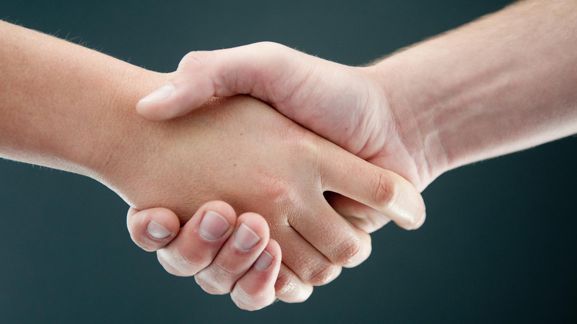 Zwei Personen geben sich die Hand. Zwei Personen geben sich die Hand.