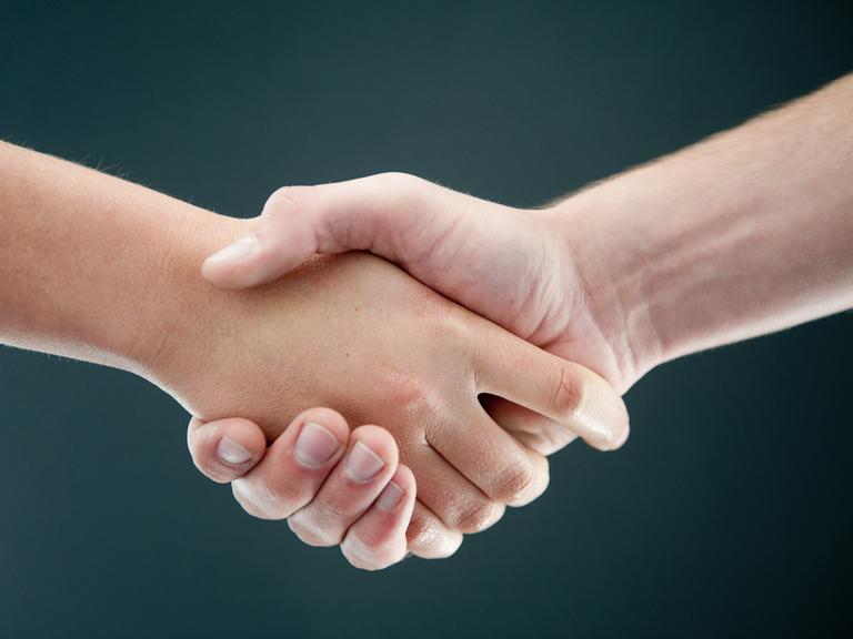 Zwei Personen geben sich die Hand. 