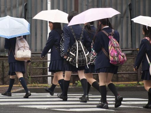 Schülerinnen in Japan. Mädchen gekleidet in Schuluniform überqueren einen Zebrastreifen.