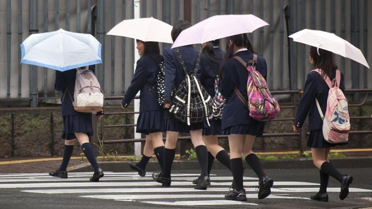 Schülerinnen in Japan. Mädchen gekleidet in Schuluniform überqueren einen Zebrastreifen. Schülerinnen in Japan. Mädchen gekleidet in Schuluniform überqueren einen Zebrastreifen.