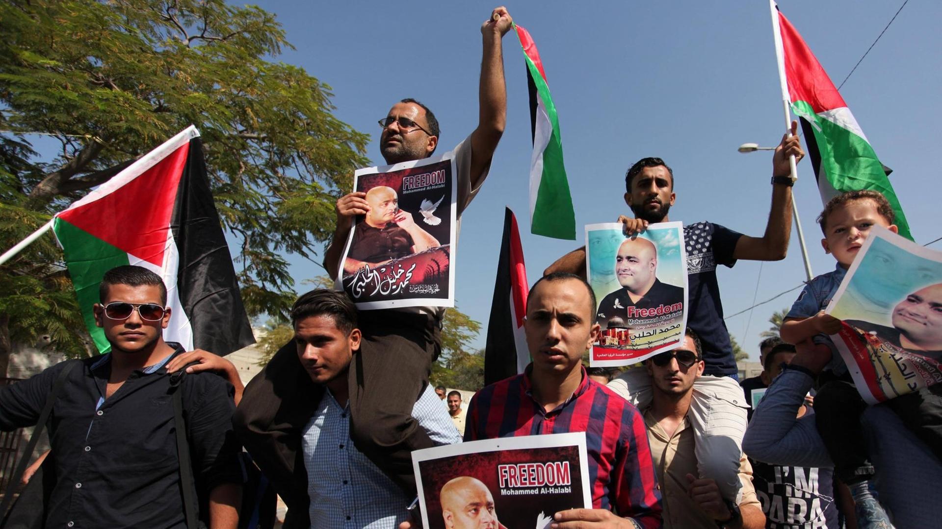 Palästinenser halten Flaggen und Bilder von Mohammed el Halabi hoch.