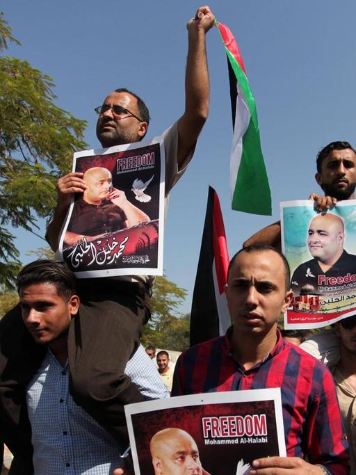 Palästinenser halten Flaggen und Bilder von Mohammed el Halabi hoch.