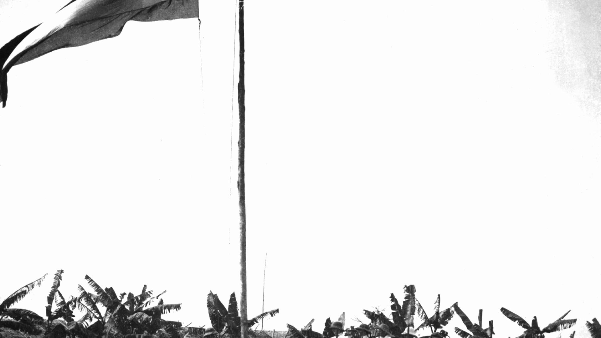 Auf einem Militärstützpunkt in der deutschen Kolonie Kamerun wird von in Tropenanzüge gekleideten Männern eine Fahne gehisst (undatierte Aufnahme aus der Kolonialzeit). Von 1884 bis zum Ersten Weltkrieg war Kamerun eine deutsche Kolonie, dann wurde es 1916 unter Großbritannien und Frankreich aufgeteilt. Auf einem Militärstützpunkt in der deutschen Kolonie Kamerun wird von in Tropenanzüge gekleideten Männern eine Fahne gehisst (undatierte Aufnahme aus der Kolonialzeit). Von 1884 bis zum Ersten Weltkrieg war Kamerun eine deutsche Kolonie, dann wurde es 1916 unter Großbritannien und Frankreich aufgeteilt.