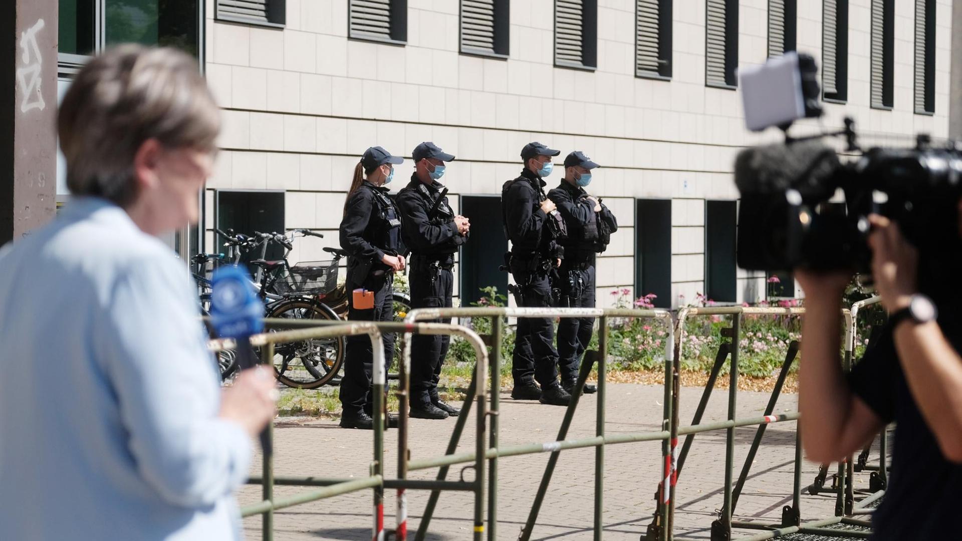 Polizisten und Journalisten stehen vor dem Landgericht Magdeburg, im Vordergrund eine Reporterin und ein Kameramann.