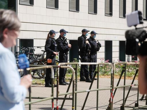 Polizisten und Journalisten stehen vor dem Landgericht Magdeburg, im Vordergrund eine Reporterin und ein Kameramann.