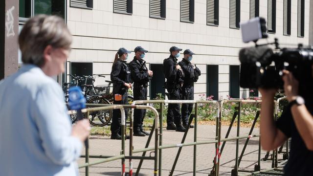 Polizisten und Journalisten stehen vor dem Landgericht Magdeburg, im Vordergrund eine Reporterin und ein Kameramann.