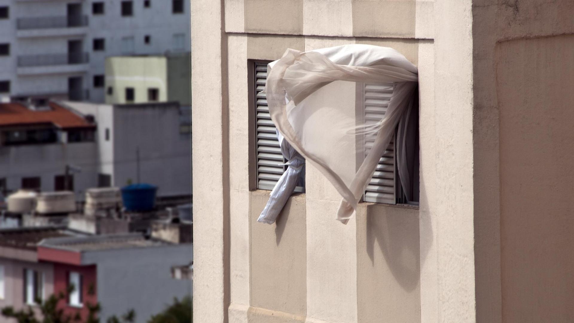 Ein Vorhang weht aus einem offenem Fenster. Ein Vorhang weht aus einem offenem Fenster.