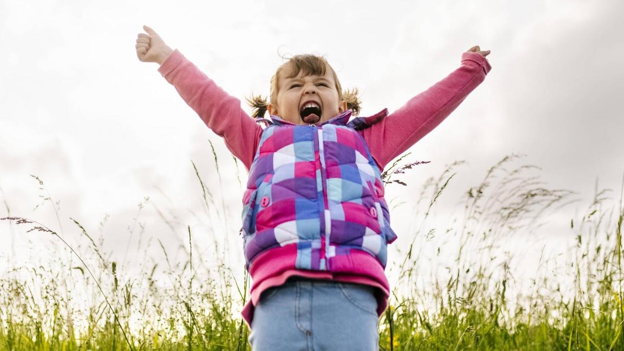 Ein glücklicher Moment und ein kleines Mädchen wirft vor Freude dabei die Arme in die Luft. Ein glücklicher Moment und ein kleines Mädchen wirft vor Freude dabei die Arme in die Luft.
