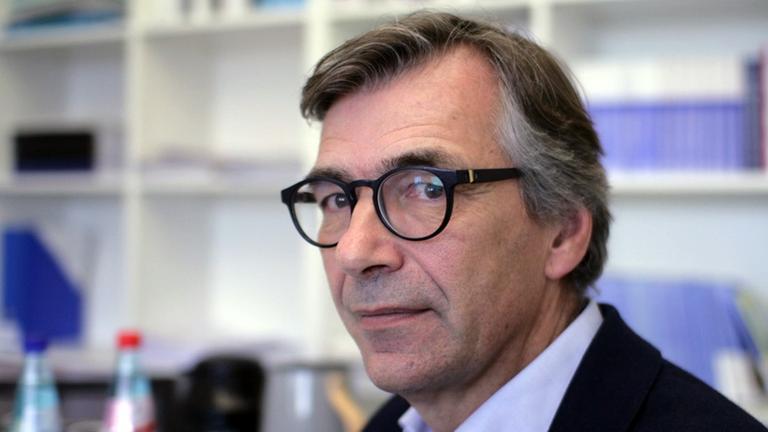 Christopher Daase, Dissidenzforscher an Goethe-Universität Frankfurt am Main. Ein älterer Mann mit Brille und kurzen Haaren sitzt in einem Büro und blickt in die Kamera. Christopher Daase, Dissidenzforscher an Goethe-Universität Frankfurt am Main. Ein älterer Mann mit Brille und kurzen Haaren sitzt in einem Büro und blickt in die Kamera.