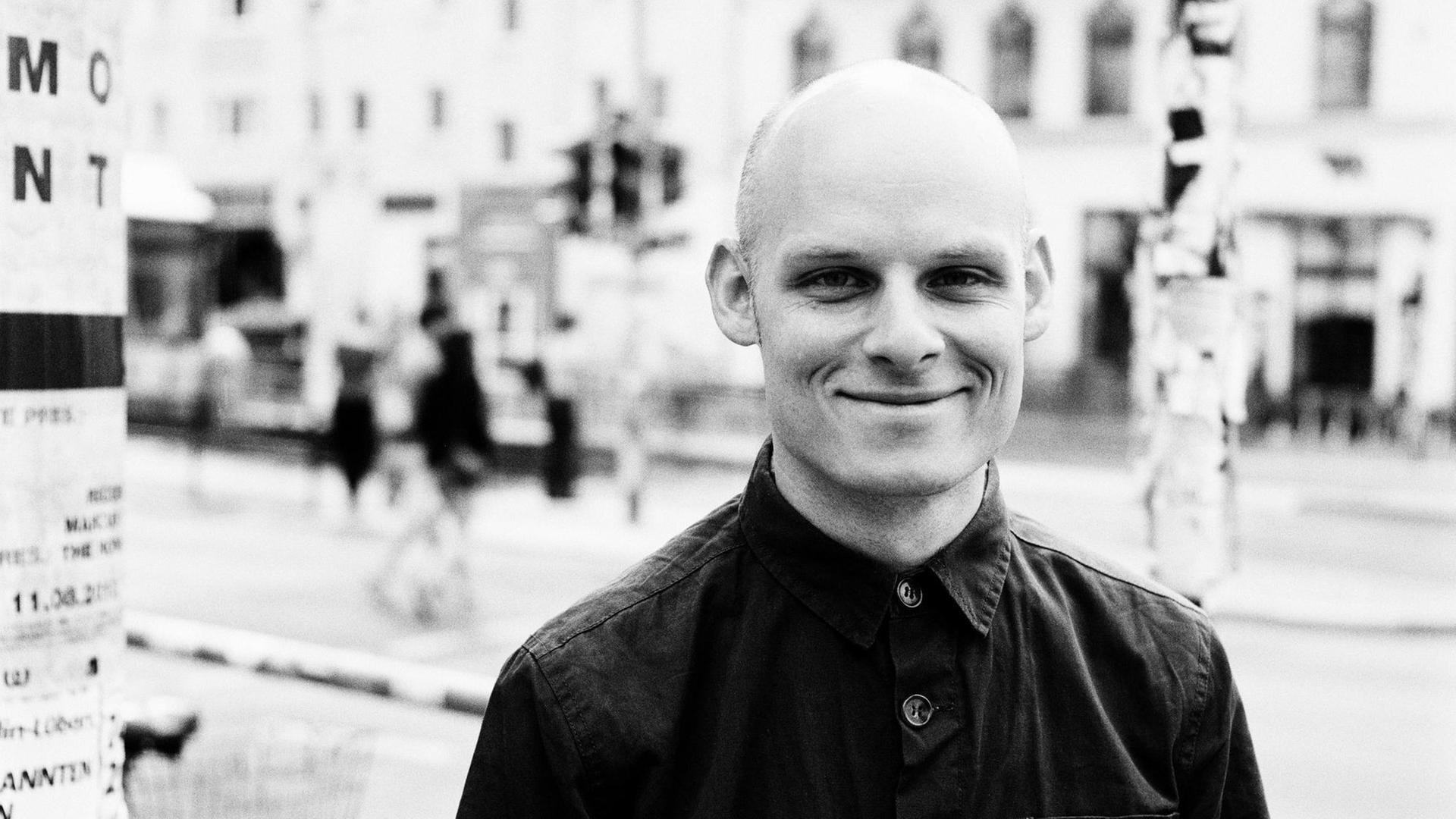 Der Jazzschlagzeuger Eric Schaefer, im Hintergrund verschwommen Straßenrand mit Häuserzeile Der Jazzschlagzeuger Eric Schaefer, im Hintergrund verschwommen Straßenrand mit Häuserzeile