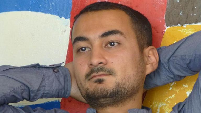 Ein Mann lehnt mit verschränkten Armen hinter dem Kopf an einer Wand. Ein Mann lehnt mit verschränkten Armen hinter dem Kopf an einer Wand.