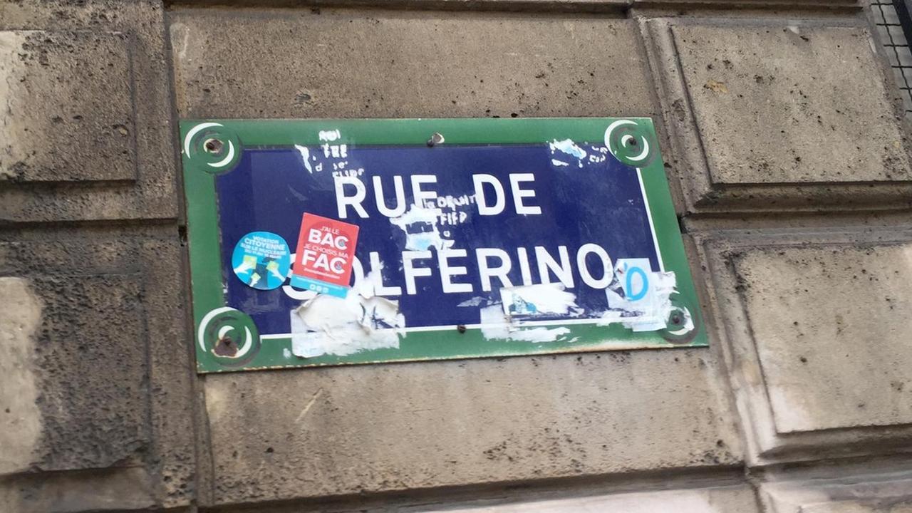 Ein blaues Straßenschild mit grünem Rand und der weißen Aufschrift "Rue de Solférino" hängt an einer Hauswand in Paris