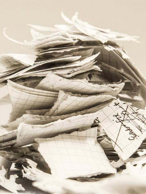 Ein Haufen von beschriebenen und zerissenen Papierschnipsel liegt übereinander.