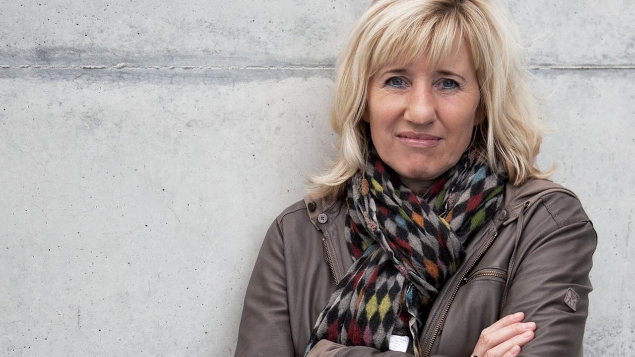Die Schriftstellerin und Doping-Expertin Ines Geipel, die Arme verschränkt, an eine graue Betonmauer gelehnt. Die Schriftstellerin und Doping-Expertin Ines Geipel, die Arme verschränkt, an eine graue Betonmauer gelehnt.