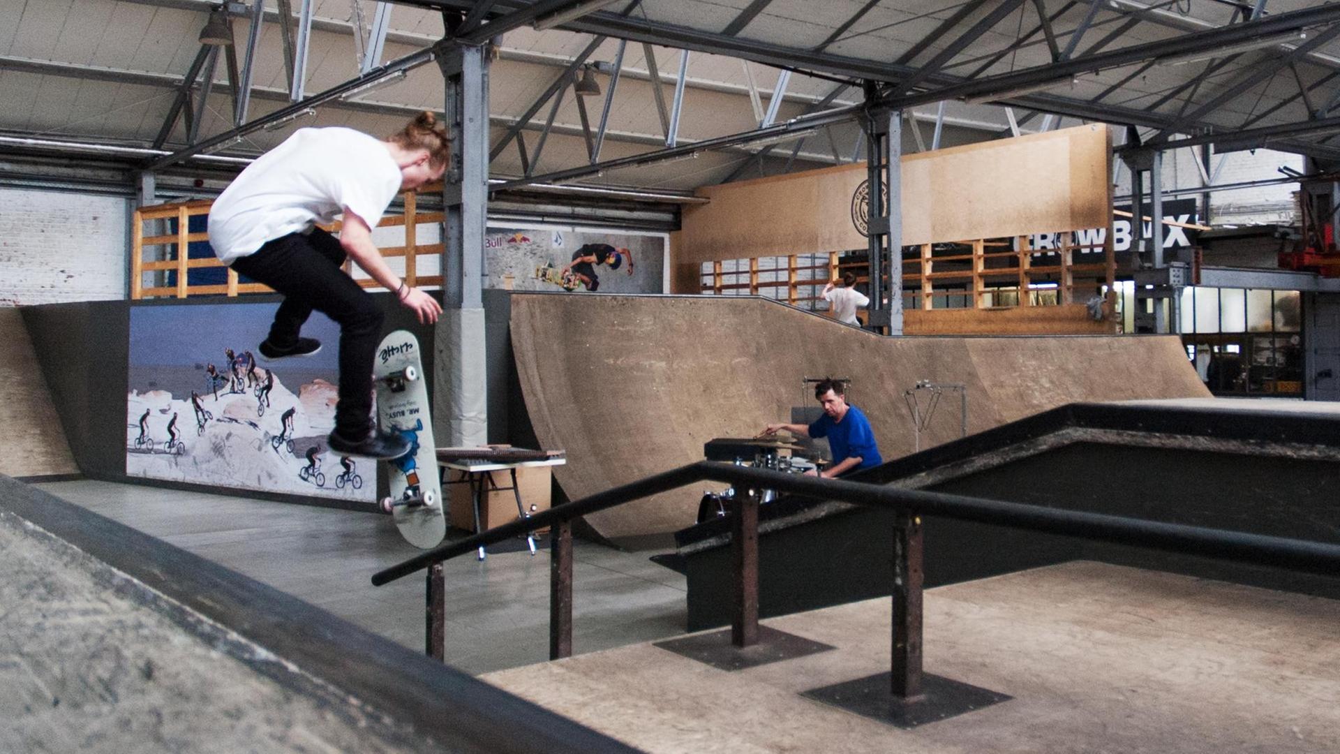 Ein Skater springt von einem Geländer, das in einem Skateboard als Hindernis aufgebaut ist. Ein Skater springt von einem Geländer, das in einem Skateboard als Hindernis aufgebaut ist.