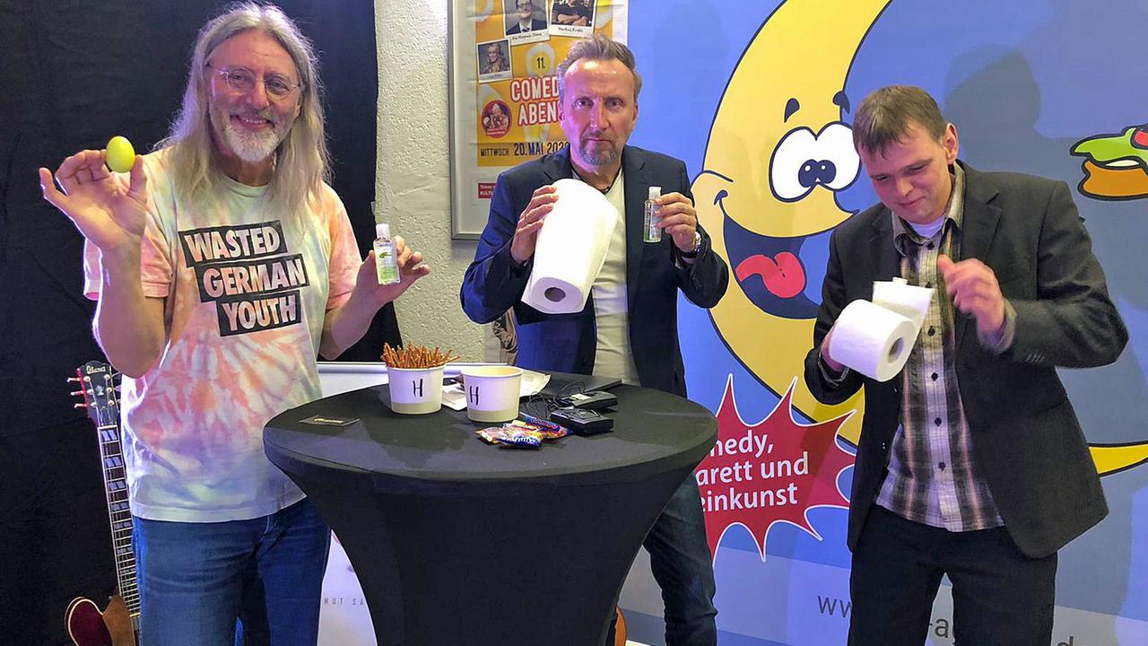 Drei Männer an Stehtischen. Sie halten Desinfektionsmittel und Klopapier in den Händen. Drei Männer an Stehtischen. Sie halten Desinfektionsmittel und Klopapier in den Händen.