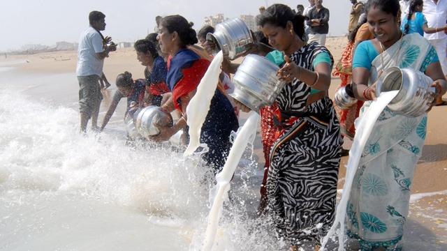 Frauen in Chennai in Indien gießen am zwölften Jahrestag der Tsunami-Katastrophe Milch ins Meer.