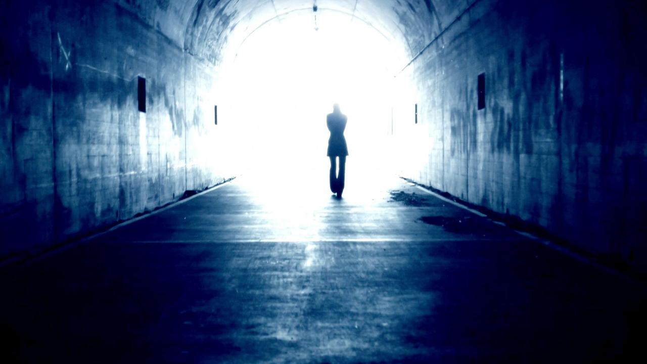 Schattenriss eines Mannes, der durch einen Tunnel ins Licht geht. Schattenriss eines Mannes, der durch einen Tunnel ins Licht geht.